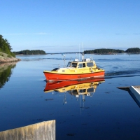 The Ocean Mapping Group’s small red and yellow vessel motors over a glassy sea.